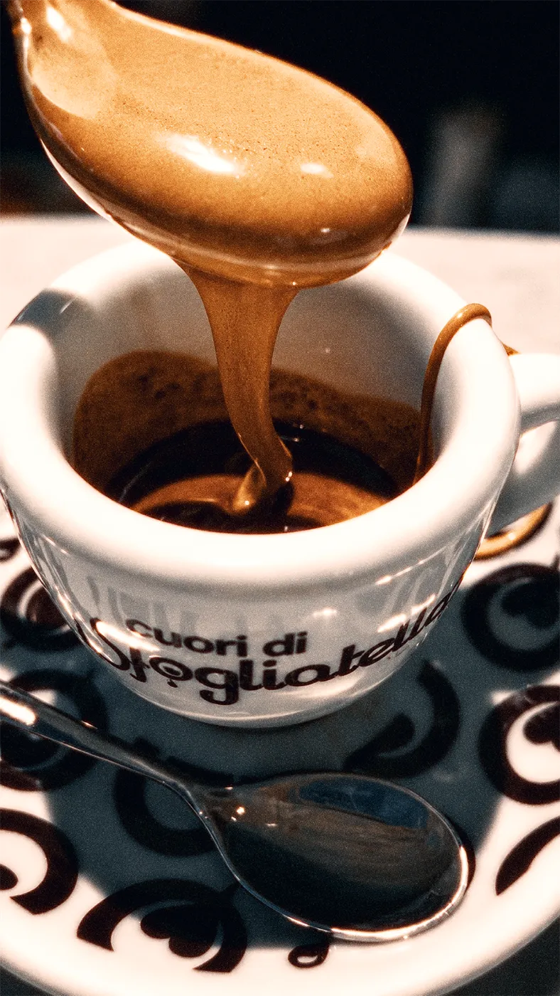 Cremina cayendo desde una cuchara sobre una taza de espresso.